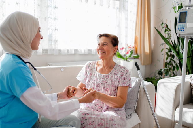 Nurse holding patient hand while visiting in the patient's home