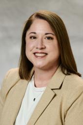 Professional portrait of Toni (Antoinette) Coe with light gray muslin background. Toni is wearing a beige suit .