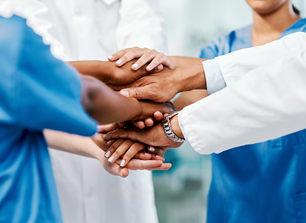 Medical staff overlaying hands in a huddle stance