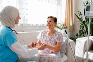 Female nurse talking to  in female patient's home